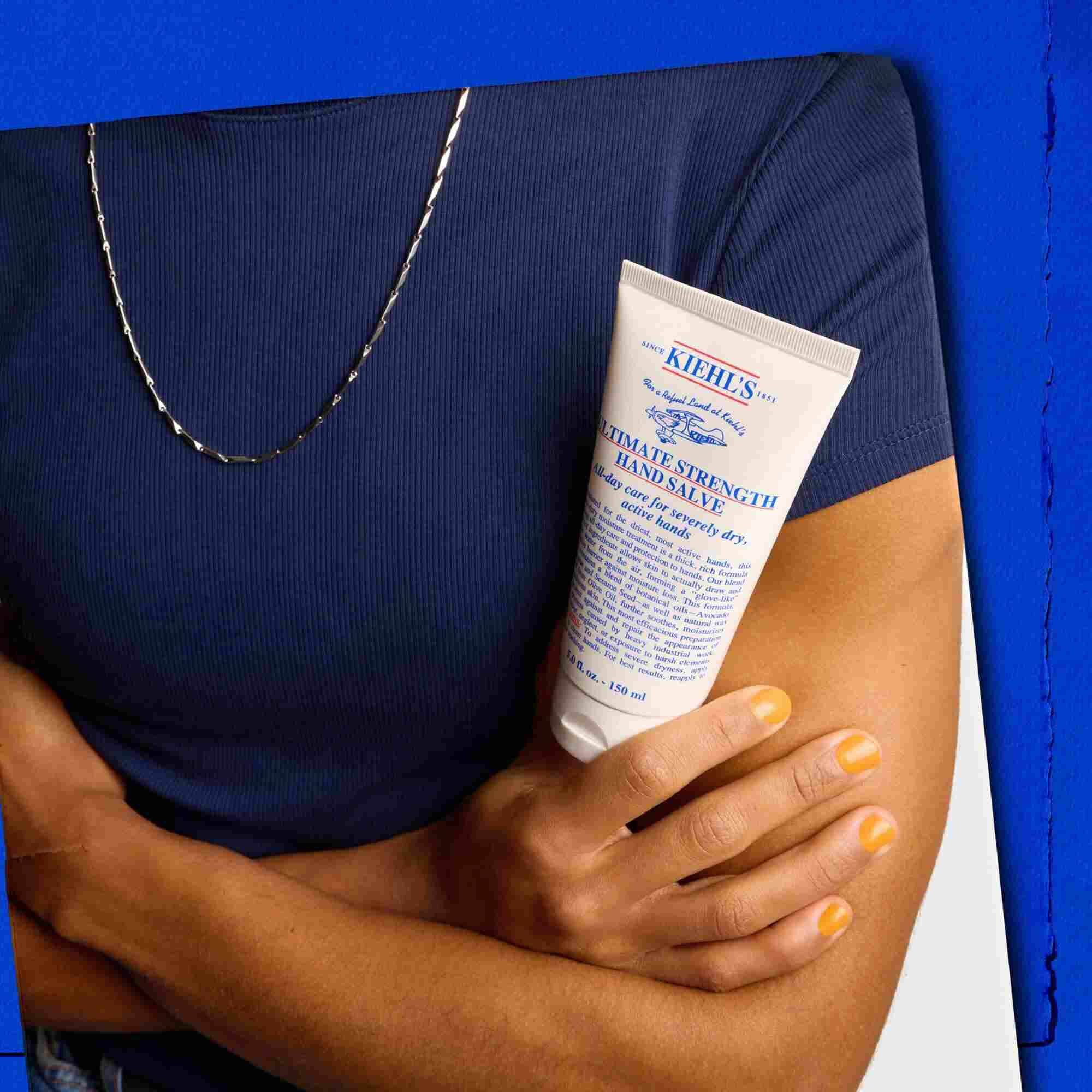 Model drži tubo Kiehl's Ultimate Strength Hand Salve