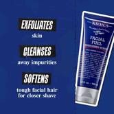 Tuba Facial Fuel Energizing Scrub na temno modrem ozadju. Besedilo se glasi: »Odstrani odmrle celice, očisti nečistoče in zmehča trde dlake na obrazu za tesnejše britje.«