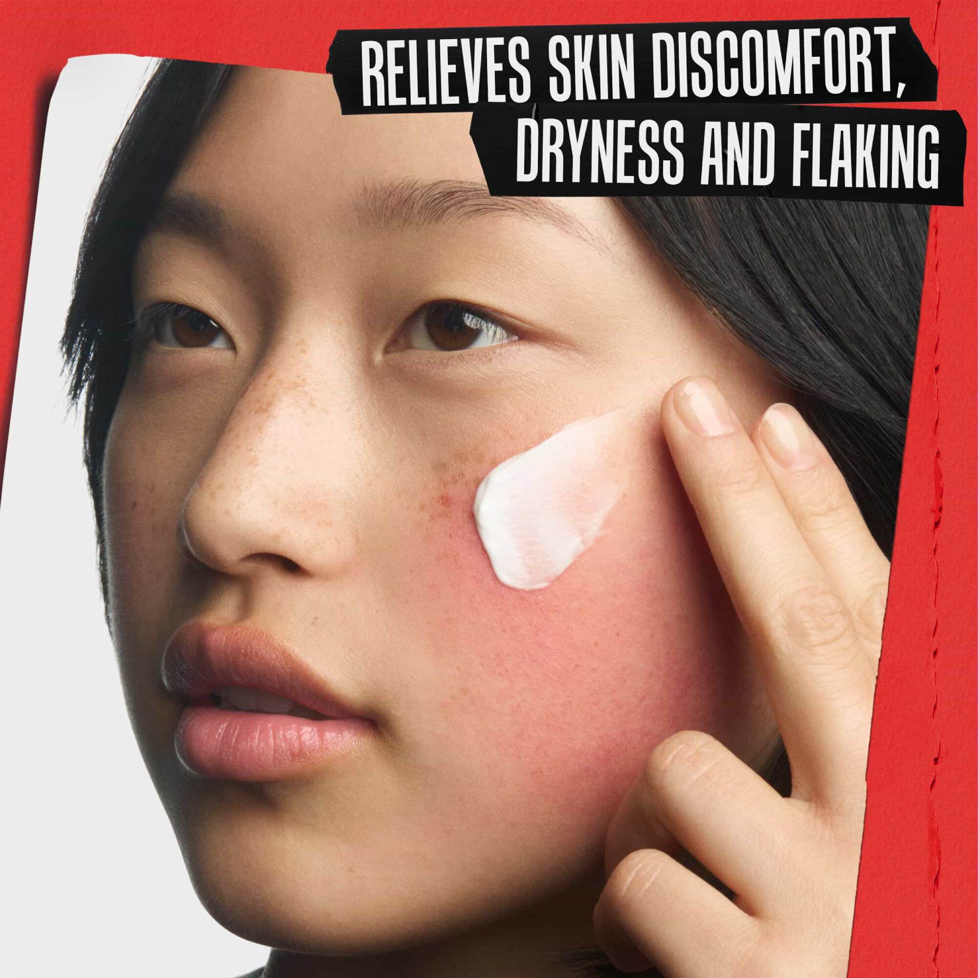 Bližinski posnetek nanašanja obnavljajoče kreme na razdražen obraz. Besedilo se glasi: BLAŽI NELAGODJE, SUHOST IN LULŠČENJE KOŽE.