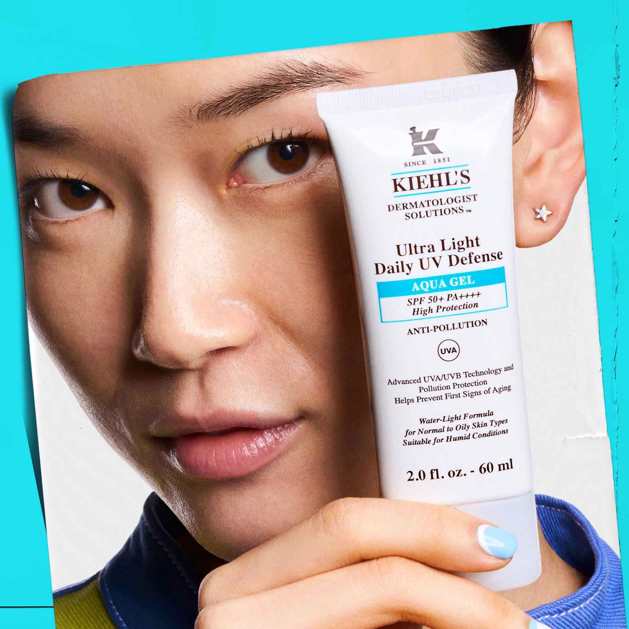 Model drži tubo Ultra Light Daily UV Defense Aqua Gel, kar prikazuje prenosljivost in enostavnost uporabe.