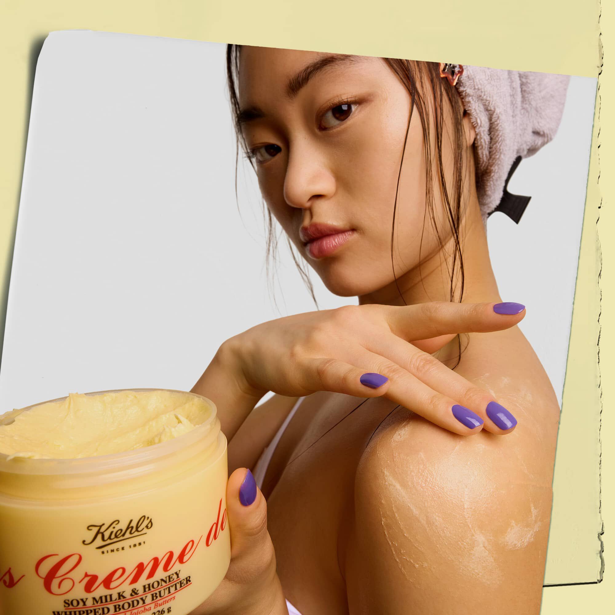 Model drži posodico in nanaša maslo za telo Kiehl's Creme de Corps Whipped Butter