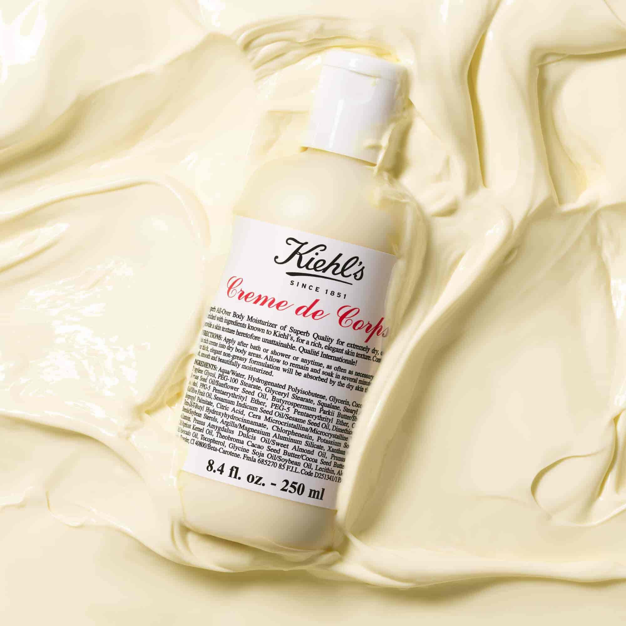 Steklenička Kiehl's Creme de Corps v veliki količini teksturiranega losjona za telo