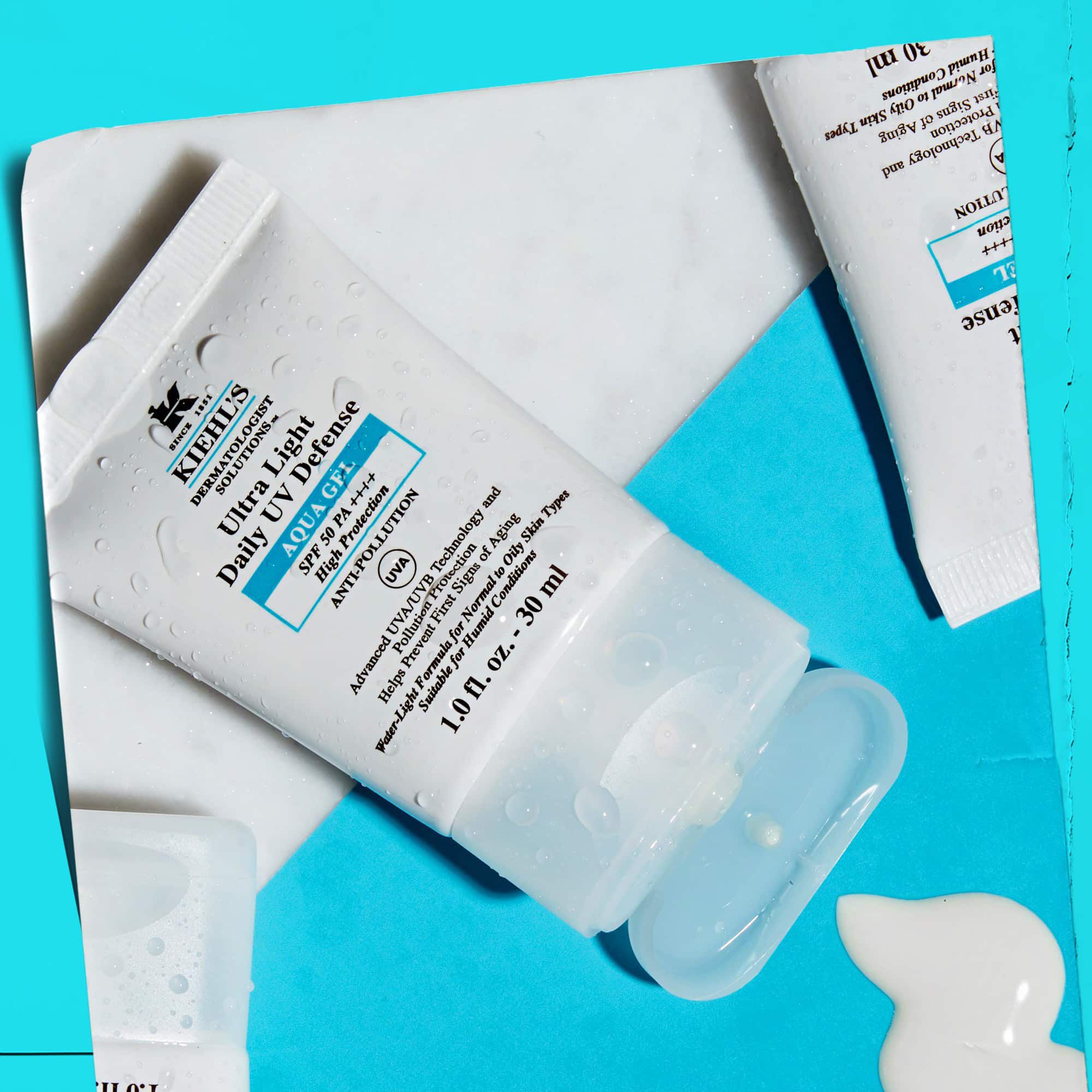 Položitev več tub Ultra Light Daily UV Defense Aqua Gel na marmorno površino, ki prikazuje njihovo privlačnost življenjskega sloga.