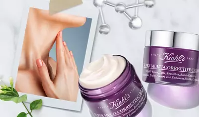 A close-up of a woman's hand gently touching her neck, accompanied by Kiehl’s Super Multi-Corrective Cream and a decorative photo backdrop featuring plants and scientific glassware.