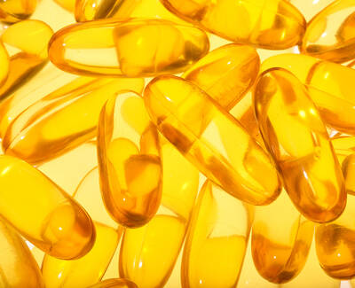 A close-up view of numerous translucent yellow gel capsules arranged closely together on a light background.