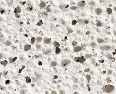 Close-up view of a porous, white-textured surface with small holes and irregular patterns.