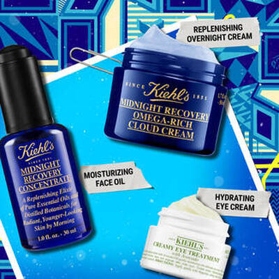 Alt text: An assortment of Kiehl's skincare products, including a blue bottle of Midnight Recovery Concentrate, a blue jar of Omega-Rich Cloud Cream, and a white jar of Creamy Eye Treatment, placed against a colorful patterned background.