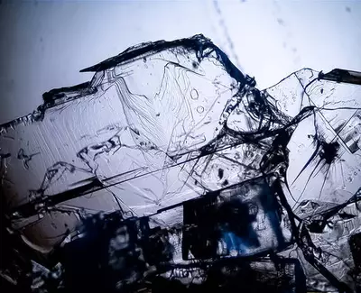 Close-up of translucent, jagged ice crystals, reflecting light and showcasing intricate patterns and textures.